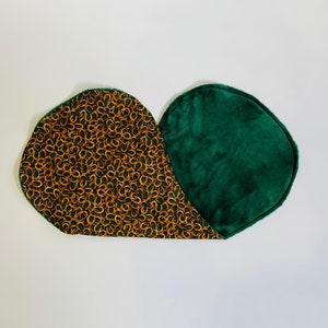May include: Two cloth pads. One pad has a dark green, soft, velvety texture. The other pad has a dark green background with a pattern of gold horseshoes. The pads are designed with rounded edges and a curved shape.