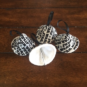 May include: Four white fabric cone-shaped ornaments with black Star Wars text and black ribbon hangers.