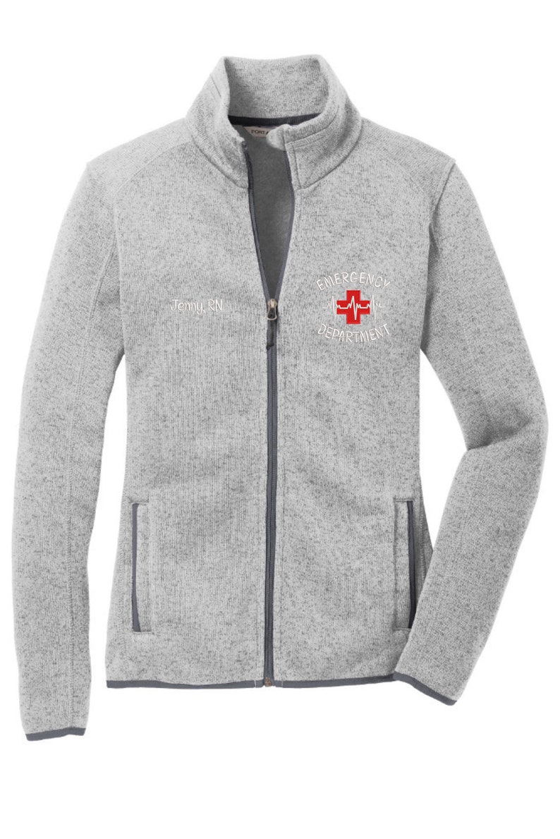 May include: A gray fleece zip-up jacket with a white embroidered logo that says "Emergency Department" with a red cross and a heartbeat symbol.