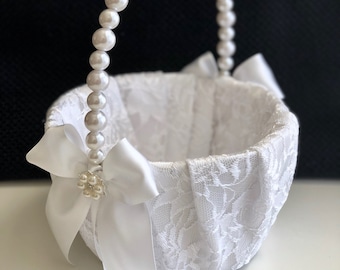 Op de afbeelding: Witte kant bloemmeisjesmand met een parelhendel en een witte satijnen strik. De mand is versierd met een parelversiering.