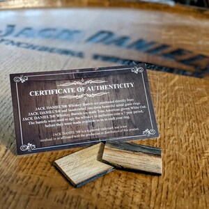 May include: A certificate of authenticity for Jack Daniel's Whiskey Barrel rings. The certificate is printed on a brown card with a gold border. The text on the certificate reads: "Jack Daniel's Whiskey Barrels are purchased directly from Jack Daniel's and handcrafted into these beautiful spiral grain rings. Jack Daniel's Whiskey Barrels are made from American grown White Oak. The barrels were used to age the whiskey to perfection over a 7 year period, before they were made available to us to craft your ring. Jack Daniel's is a registered trademark and is not involved in or affiliated with the production or distribution of this product."