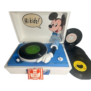 May include: A vintage blue and white Sears Solid State record player with a Mickey Mouse theme. The record player has a Mickey Mouse arm and hand, and the lid features Mickey Mouse and the words "Hi kids!". Several vinyl records are included.