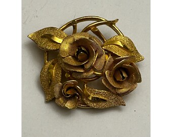 Broche ronde à trois roses, couleur or, avec fleurs et feuilles texturées.