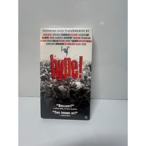 May include: A VHS tape for the music documentary "Hype!" featuring rare performances by various bands. The cover has a red "Hype!" title over a crowd image, with band names listed above. Includes quotes "Brilliant!" and "Two Thumbs Up!"