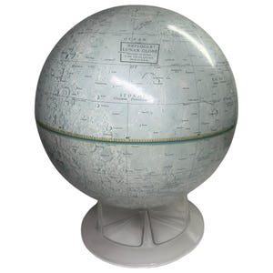 May include: A Replogle Lunar Globe, featuring a detailed map of the moon's surface. The globe is supported by a clear plastic base. The text on the globe reads "Replogle Lunar Globe" and the diameter is 12 inches.
