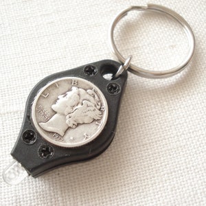Può includere: Un portachiavi nero con una torcia elettrica e una moneta da dieci centesimi d'argento del 1937 di Mercury incorporata nella parte anteriore. Il portachiavi ha un anello di metallo argentato.