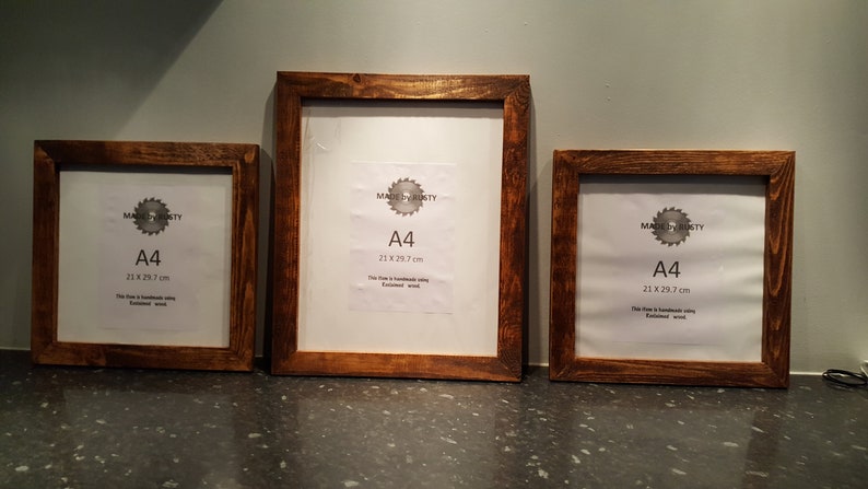 Peut inclure: Trois cadres en bois avec une finition marron fonc&eacute;. Chaque cadre contient une feuille de papier blanche avec le texte "A4 21 x 29,7 cm". Les cadres sont faits &agrave; la main et semblent &ecirc;tre en bois fini.