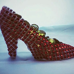 May include: A red and gold high-heeled shoe covered in sequins.