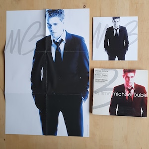 Puede incluir: Un póster promocional y un CD para el álbum de Michael Bublé "It's Time". El póster presenta una foto de Michael Bublé con un traje negro y corbata, con el título del álbum "It's Time" escrito en blanco. La portada del CD presenta una foto similar de Michael Bublé, con el título del álbum "It's Time" escrito en blanco y el nombre del artista "Michael Bublé" escrito en negro.