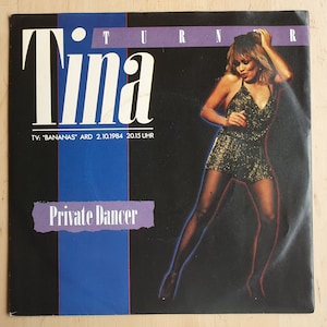 Op de afbeelding: Een zwart-witte platenhoes met een foto van Tina Turner in een glinsterende gouden jurk. De tekst "Tina Turner" staat in grote witte letters bovenaan de hoes. De tekst "Private Dancer" staat in witte letters op een paarse achtergrond onderaan de hoes. De tekst "TV: "Bananas" ARD 2.10.1984 20.15 UHR" staat in witte letters onderaan de hoes.