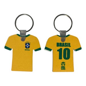 May include: A yellow and green soccer jersey keychain with the word "BRASIL" and the number "10" printed on it. The keychain has a silver ring and a clear plastic loop.