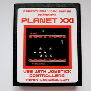 May include: A black rectangular video game cartridge with a white label featuring the text REPENTLESS VIDEO GAMES PRESENTS PLANET XXI. The label displays a retro pixelated space shooter game graphic with red and white elements on a black background.