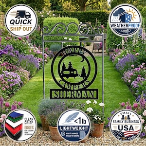 May include: Black metal garden sign with the words "Happy Campers" and a camper silhouette. The sign includes the name "Sherman" and is displayed in a garden setting with flowers and grass. The sign is lightweight and weatherproof.