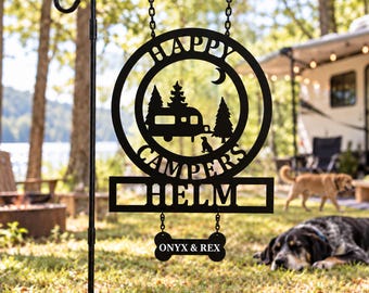 May include: A black metal garden sign hanging from a stand, featuring a circular frame with a camper, trees, a crescent moon, and a dog silhouette. The text reads HAPPY CAMPERS HELM, with a bone-shaped plaque below reading ONYX & REX.