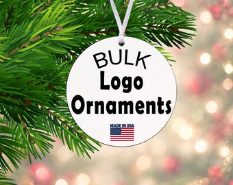 May include: A round white ornament hanging from a white ribbon. The ornament features the black text BULK Logo Ornaments and a small American flag icon with the text MADE IN USA printed in black below the flag.