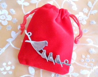 May include: A silver charm with a branch and five birds, in a red velvet drawstring bag.