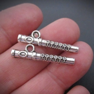 May include: Two silver-toned flute charms with a loop at the top for attaching to jewelry or other crafts.