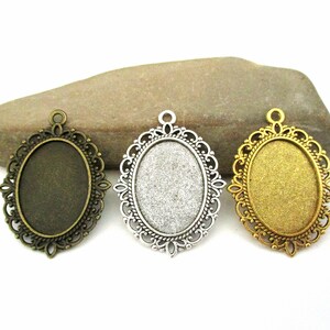 May include: Three oval-shaped pendant trays with ornate metal frames. The frames are in bronze, silver, and gold finishes.