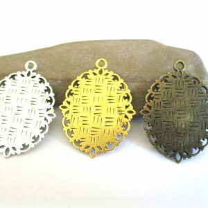May include: Three oval-shaped metal pendant blanks with a woven pattern. The blanks are silver, gold, and bronze.