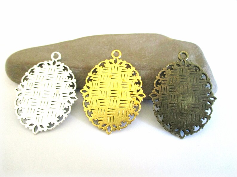 May include: Three oval-shaped metal pendant blanks with a woven pattern. The blanks are silver, gold, and bronze.