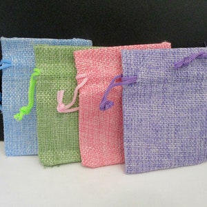 May include: Four small burlap drawstring bags in different colors: light blue, green, pink, and purple.