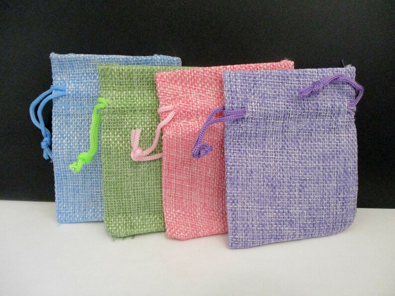 May include: Four small burlap drawstring bags in different colors: light blue, green, pink, and purple.