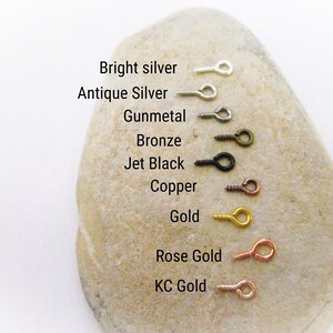 May include: A close-up of a rock with a row of eight different colored eyelet screws. The colors are bright silver, antique silver, gunmetal, bronze, jet black, copper, gold, rose gold, and KC gold.