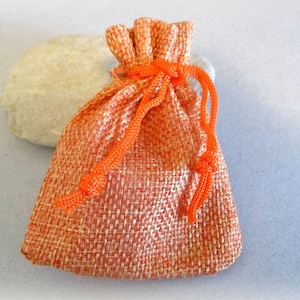 May include: A small orange burlap drawstring bag with a bright orange cord.