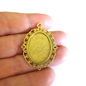 May include: Gold-toned metal pendant with an oval-shaped bezel, ideal for adding a custom touch to jewellery projects.