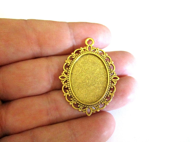 May include: Gold-toned metal pendant with an oval-shaped bezel, ideal for adding a custom touch to jewellery projects.