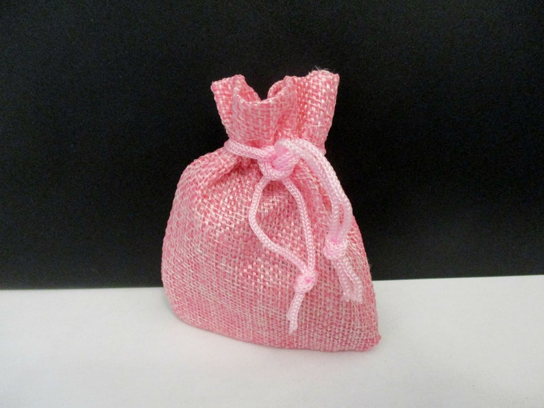 May include: A pink burlap drawstring bag with a pink ribbon closure.
