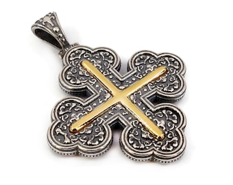 May include: A silver and gold cross pendant with an intricate design. The cross is made of two layers, with the top layer being gold and the bottom layer being silver. The pendant has a loop at the top for attaching to a chain.