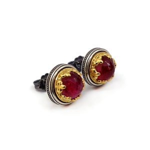 Puede incluir: Un par de pendientes de plata con cabujones de piedras preciosas rojas engastados en engastes de oro. Los pendientes tienen un diseño detallado y ornamentado.