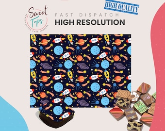 May include: A sheet of edible cake topper paper with a repeating pattern of rockets, planets, stars, and shooting stars on a dark blue background. The text "Sweet Tops" is visible in a circle at the top of the image.