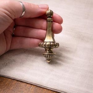 May include: A set of three ceramic mugs with a speckled, matte finish. The mugs are in shades of cream, light gray, and dark gray. Each mug has a simple, minimalist design and a rounded handle.