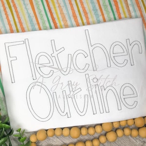 May include: White fabric with the name "Fletcher" outlined in black thread. The word "Outline" is also written in black thread below the name.