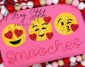 May include: Pink shirt with three embroidered yellow smiley faces with hearts. The faces have different expressions, including winking, hearts for eyes, and blowing a kiss. The text "A Gray Stitch and Design" and "Smooches" is embroidered in red.