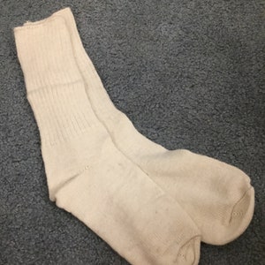 May include: A pair of white cotton socks. The socks are ribbed and have a crew length.