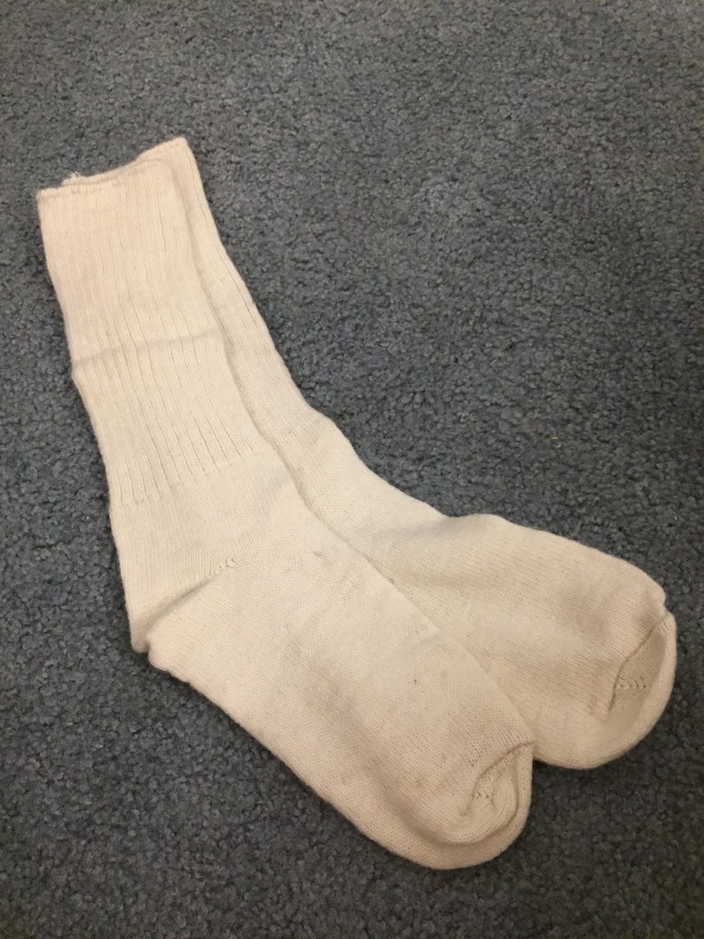 May include: A pair of white cotton socks. The socks are ribbed and have a crew length.