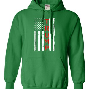 May include: Green hooded sweatshirt with a white and red American flag design. The flag has the word "TRUMP" written vertically in red.