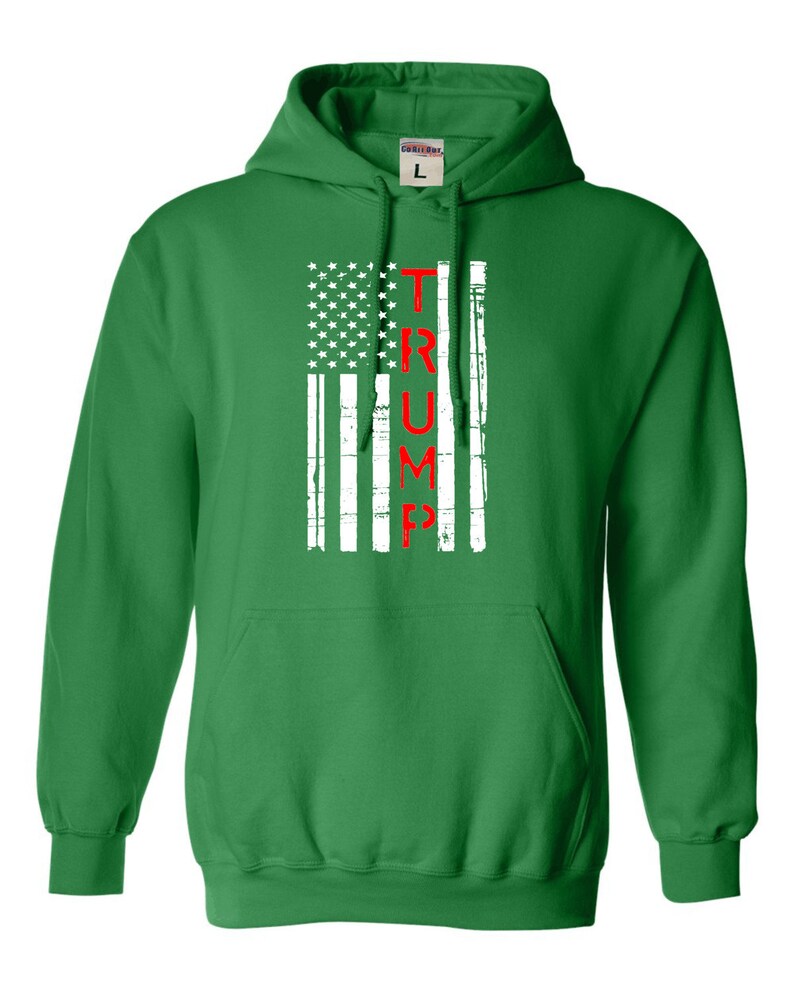 May include: Green hooded sweatshirt with a white and red American flag design. The flag has the word "TRUMP" written vertically in red.