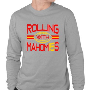 May include: A gray long-sleeve t-shirt with the text "ROLLING WITH MAHOM15S" in red and yellow. The text is surrounded by two red stripes.