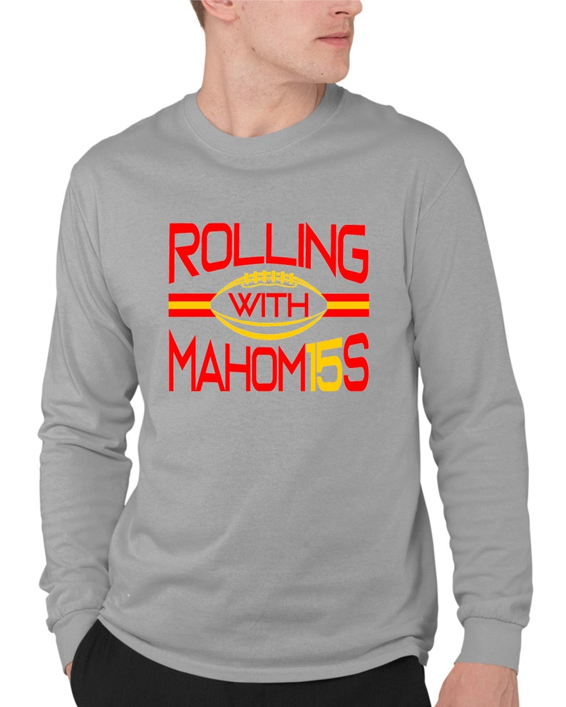 May include: A gray long-sleeve t-shirt with the text "ROLLING WITH MAHOM15S" in red and yellow. The text is surrounded by two red stripes.