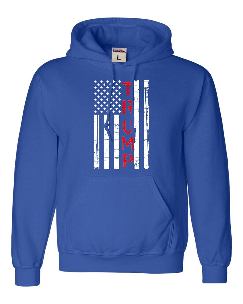 May include: A royal blue hooded sweatshirt with a white and red distressed American flag design. The word "TRUMP" is printed vertically in red on the flag.