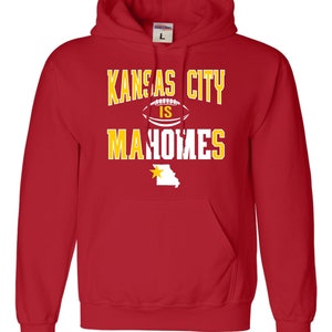 Puede incluir: Sudadera con capucha roja con el texto "Kansas City is Mahomes" en amarillo con un gr&aacute;fico de f&uacute;tbol blanco y un contorno amarillo del estado de Misuri con una estrella dorada.