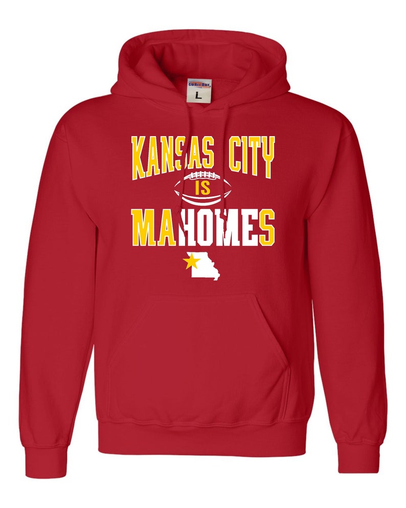 Puede incluir: Sudadera con capucha roja con el texto "Kansas City is Mahomes" en amarillo con un gr&aacute;fico de f&uacute;tbol blanco y un contorno amarillo del estado de Misuri con una estrella dorada.
