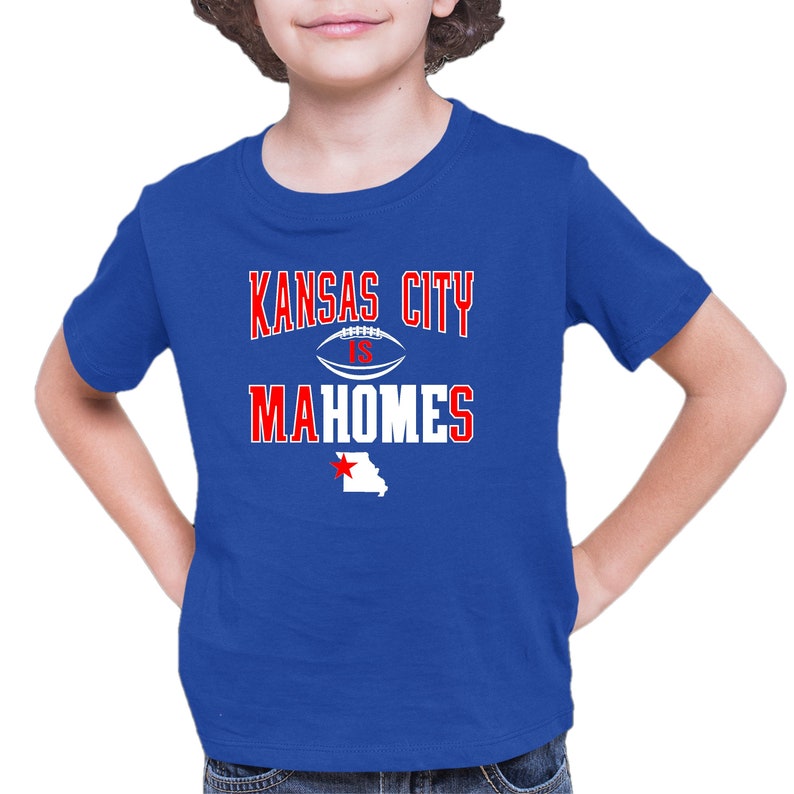K&ouml;nnte beinhalten: Ein k&ouml;nigsblaues T-Shirt mit einer wei&szlig;en Grafik, auf der "Kansas City is Mahomes" steht, mit einer wei&szlig;en Football-Grafik und einem roten Stern &uuml;ber einem wei&szlig;en Umriss des Bundesstaates Missouri.