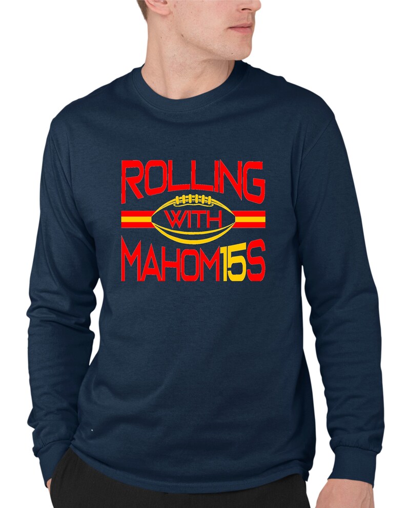May include: Navy blue long-sleeve t-shirt with a red and yellow graphic that says "Rolling with Mahomes 15". The graphic features a football with a red and yellow stripe.