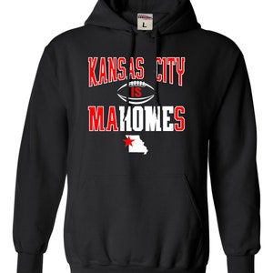 Puede incluir: Sudadera con capucha negra con texto blanco que dice "Kansas City is Mahomes" con un gr&aacute;fico de f&uacute;tbol y una estrella roja sobre un contorno blanco del estado de Misuri.