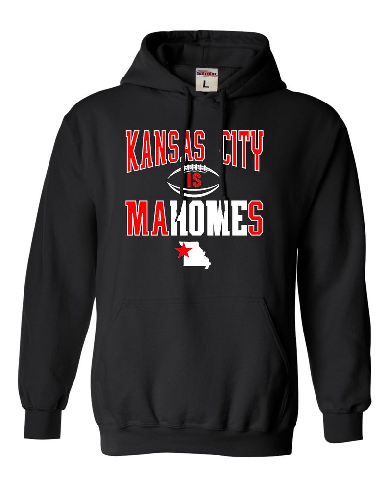 Puede incluir: Sudadera con capucha negra con texto blanco que dice "Kansas City is Mahomes" con un gr&aacute;fico de f&uacute;tbol y una estrella roja sobre un contorno blanco del estado de Misuri.